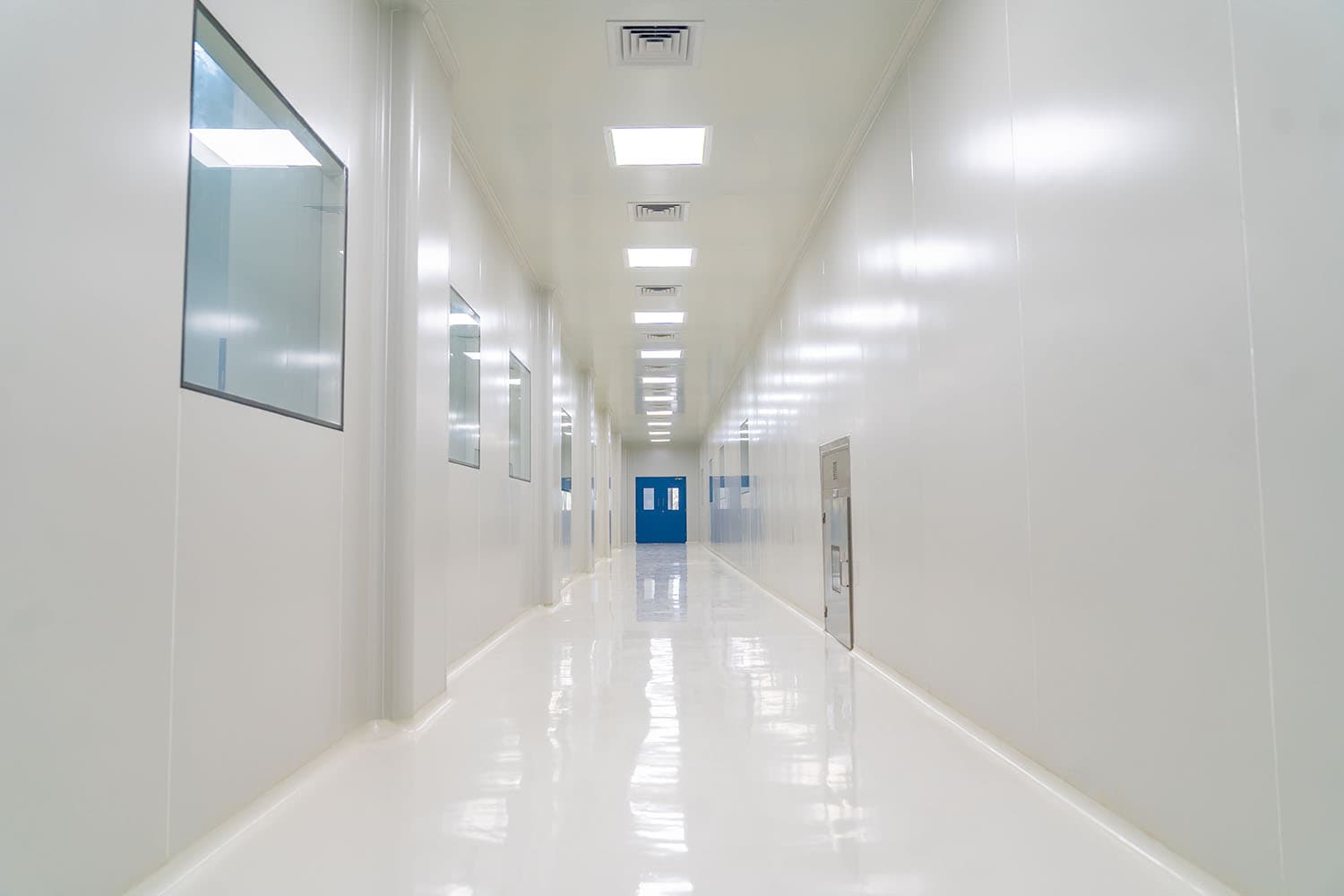 Completed cleanroom corridor with flush modular wall panels, coved junctions, vision panels and ceiling terminal filters
